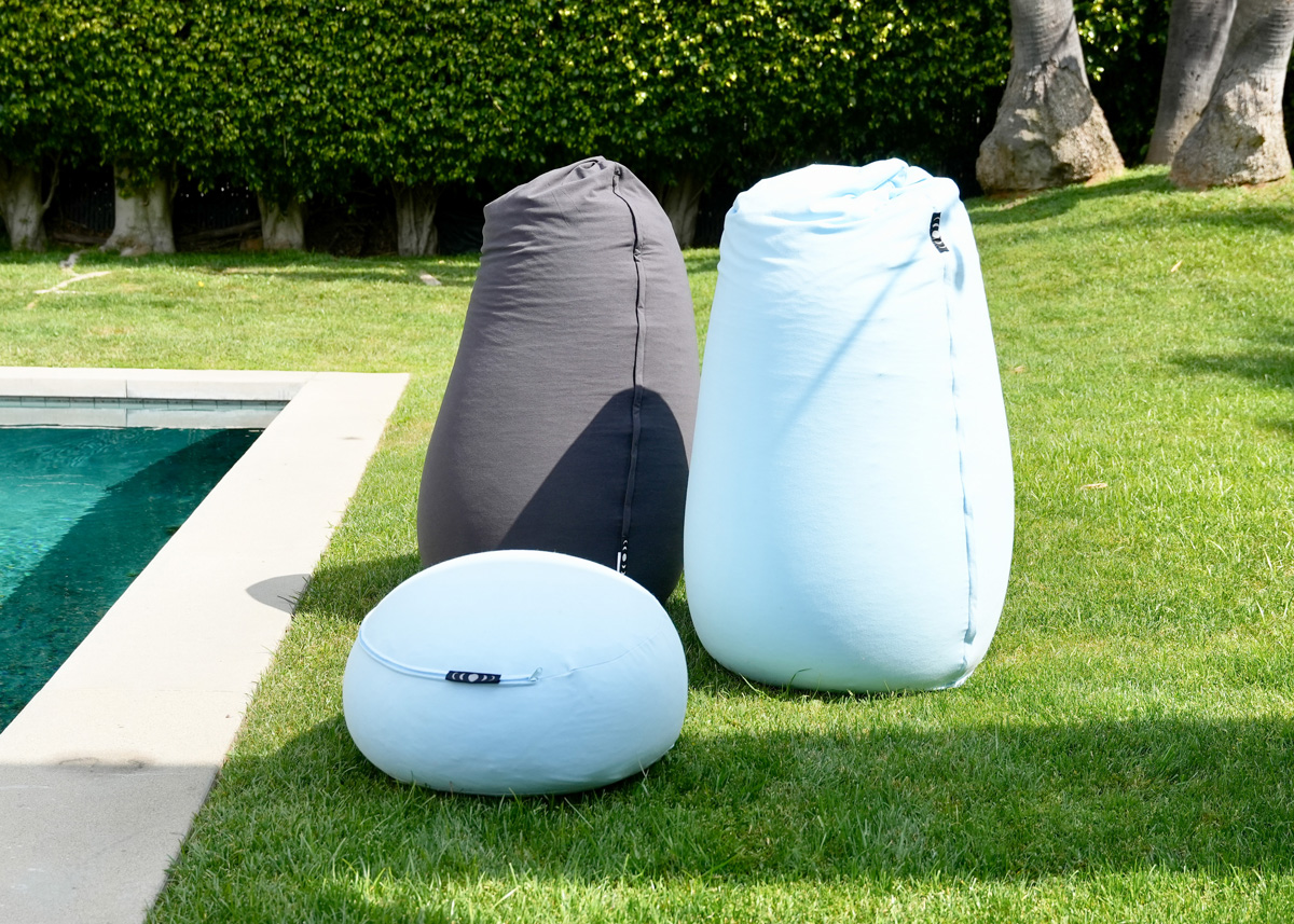 Two comfortable Moon Pod beanbag chairs and a stool, outside on a lush green lawn. 